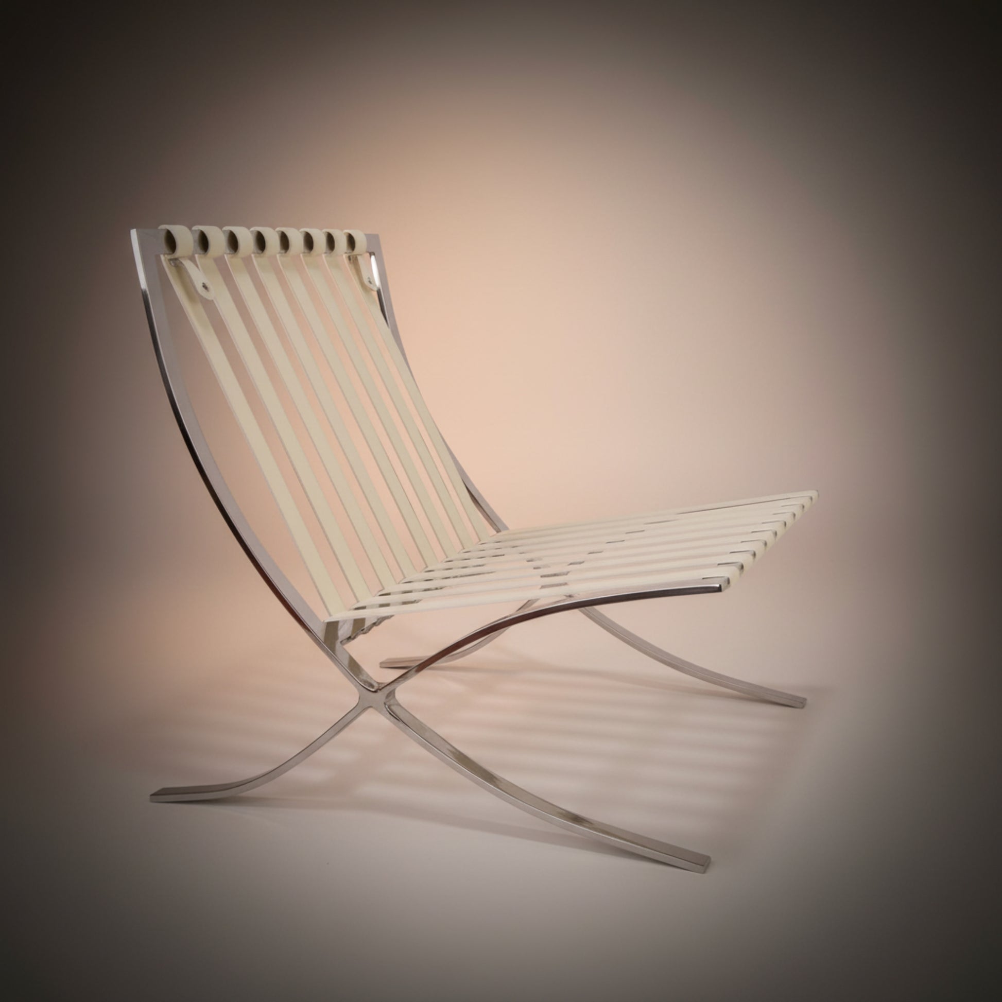 A modern Barcelona-style chair with a curved chrome metal frame and off-white woven seat and back slats.