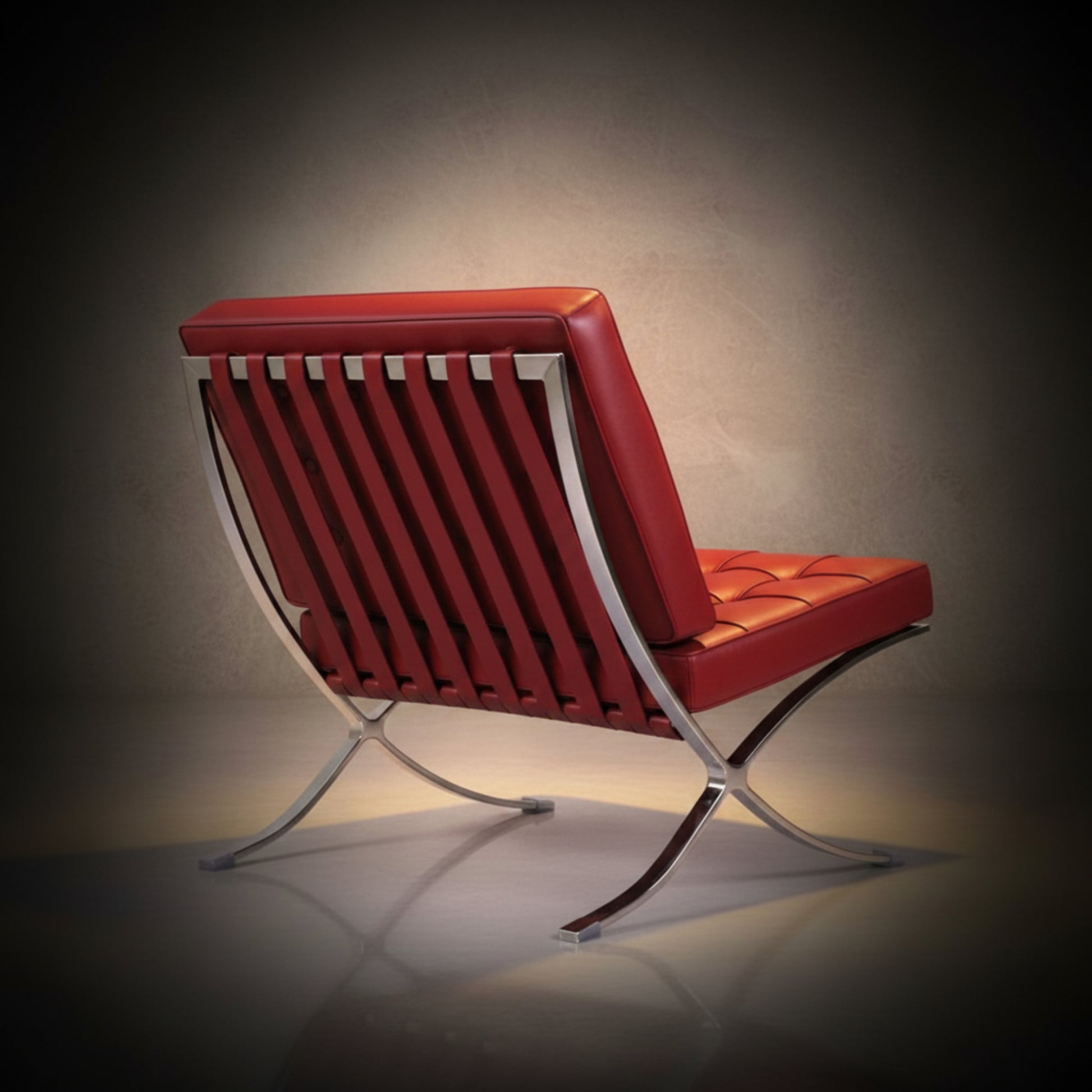 A modern lounge chair with red leather upholstery and a chrome metal frame, shown from a three-quarters angle against a dark studio background.