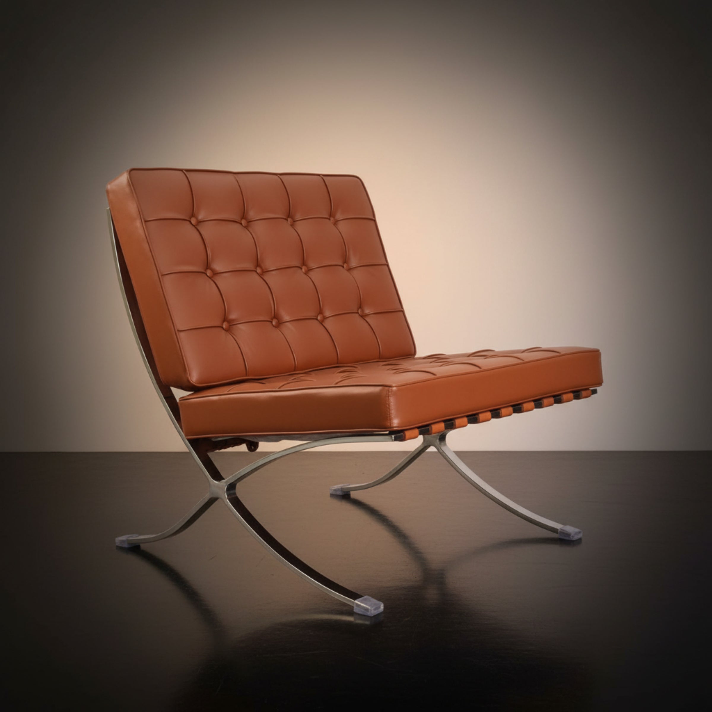 A modern Barcelona-style lounge chair with tufted cognac brown leather upholstery and a chrome metal crisscross base