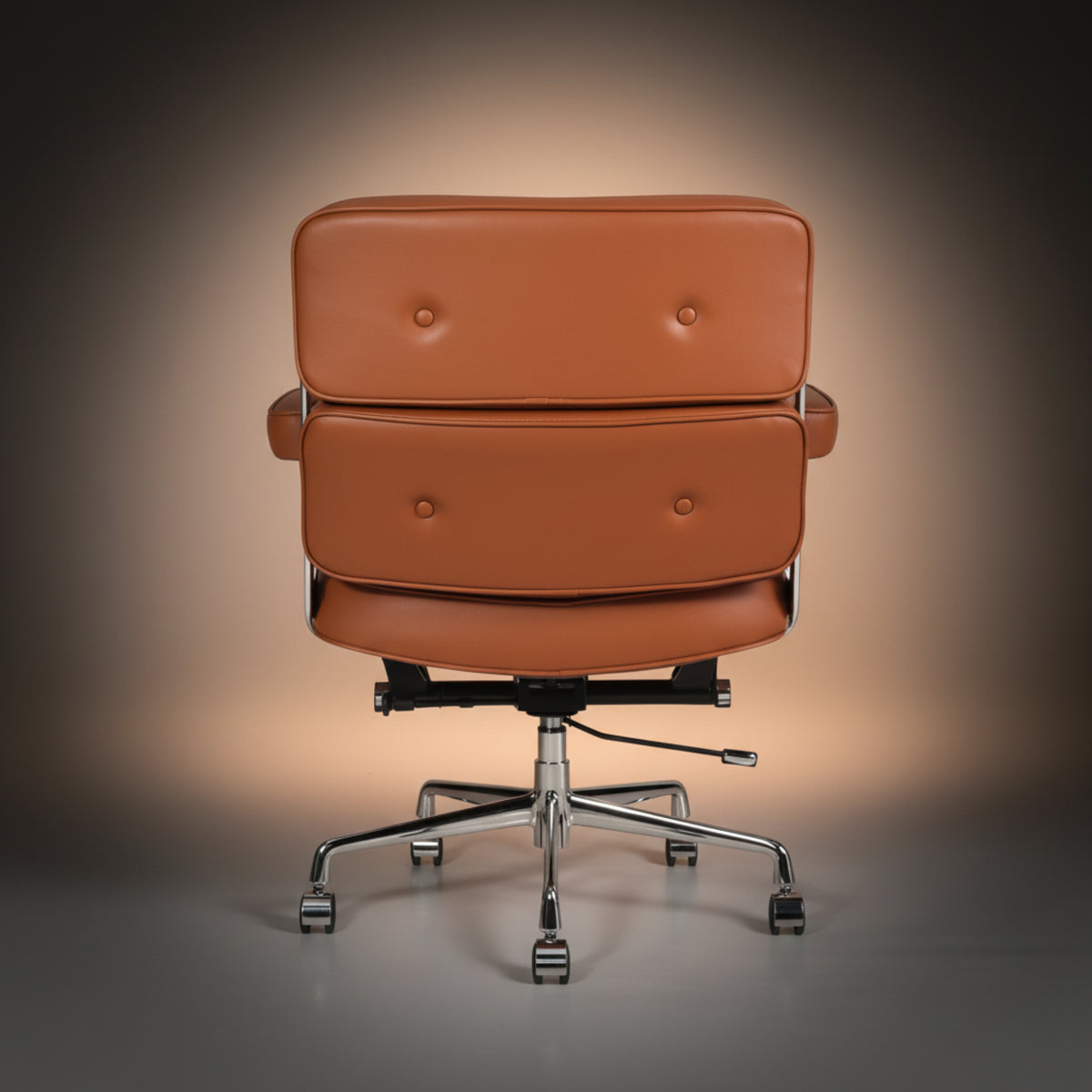 A modern lounge chair with a double tufted backrest upholstered in warm cognac brown leather, featuring chrome-finished metal armrests.
