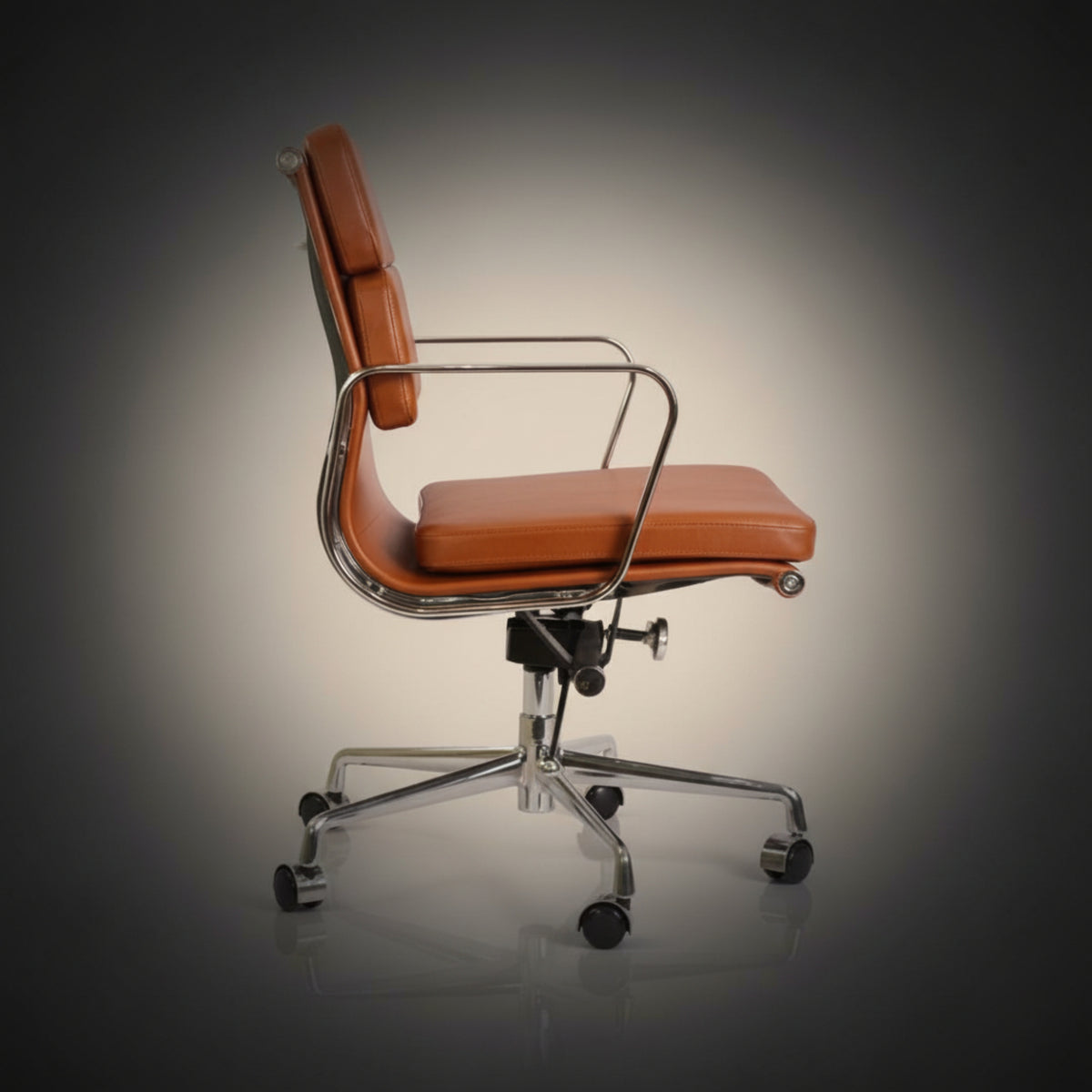 A mid-century modern office chair with orange-brown leather upholstery and a chrome metal frame.
