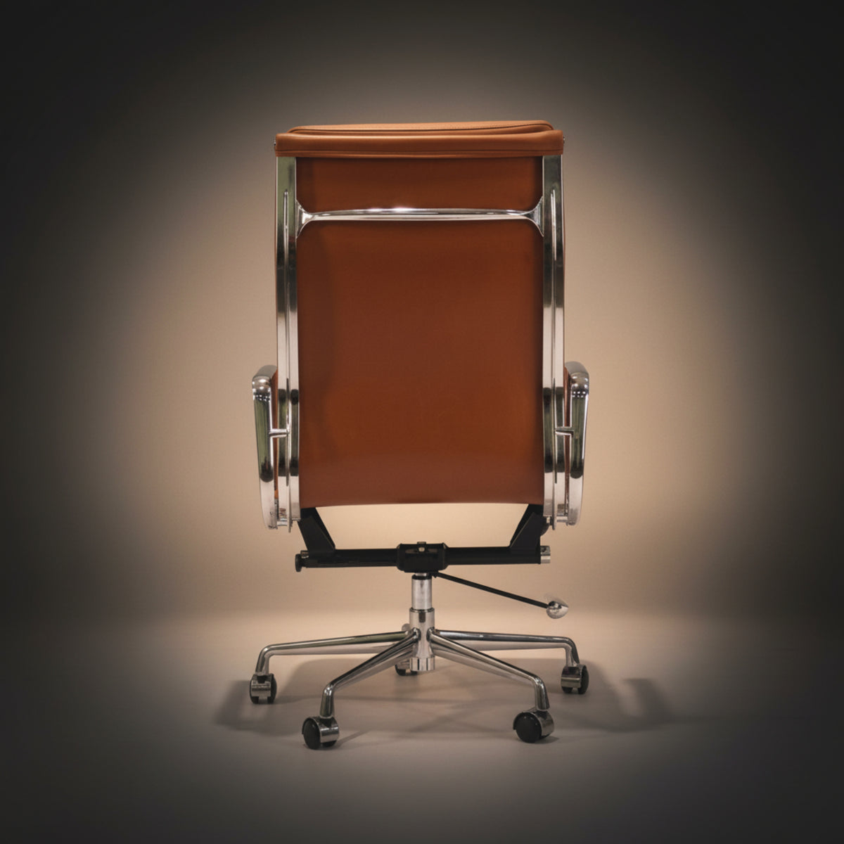 A mid-century modern office chair with a warm brown leather seat and backrest, supported by a polished chrome.